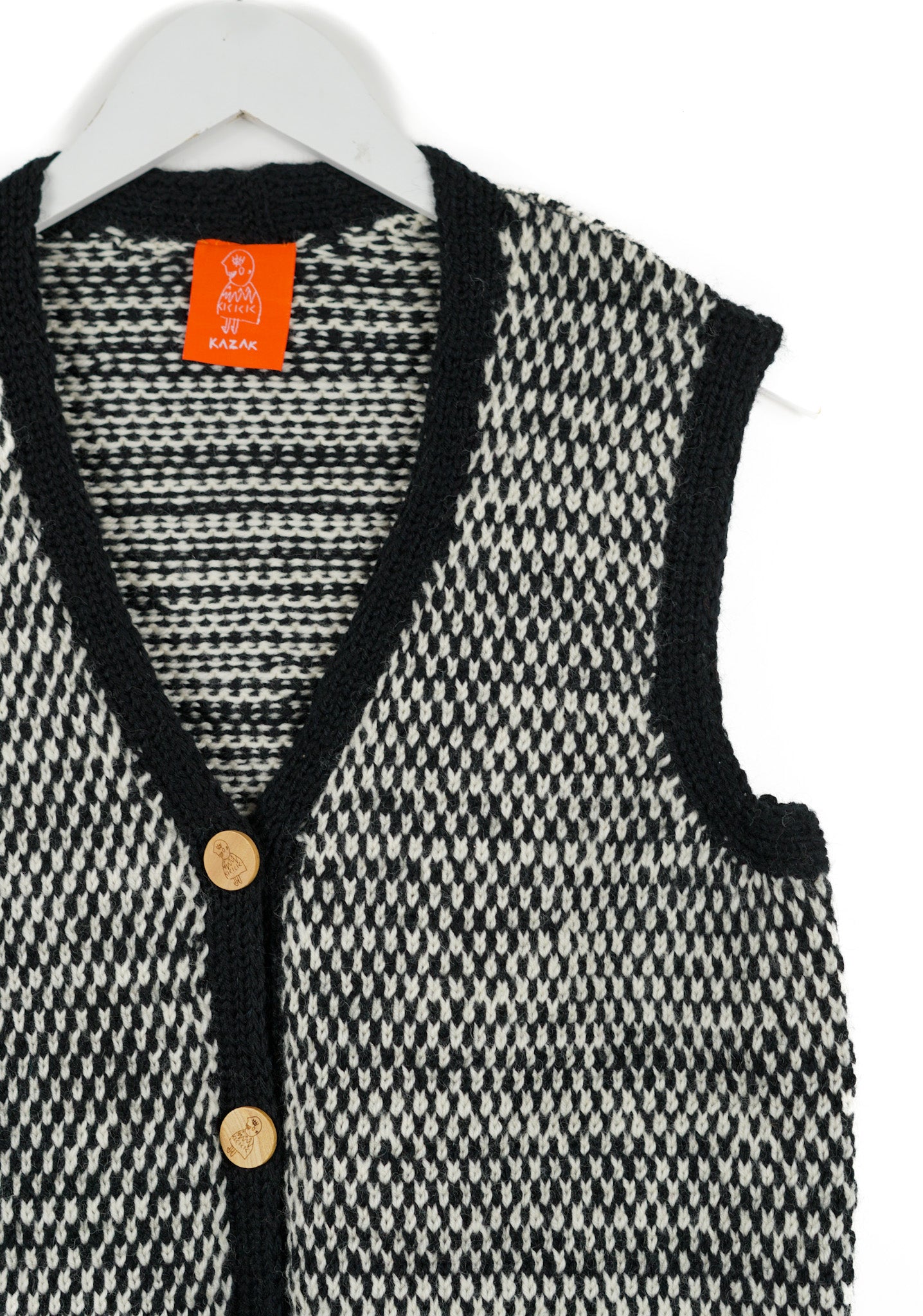 Black and white houndstooth patterned cardigan with orange tag on a white background