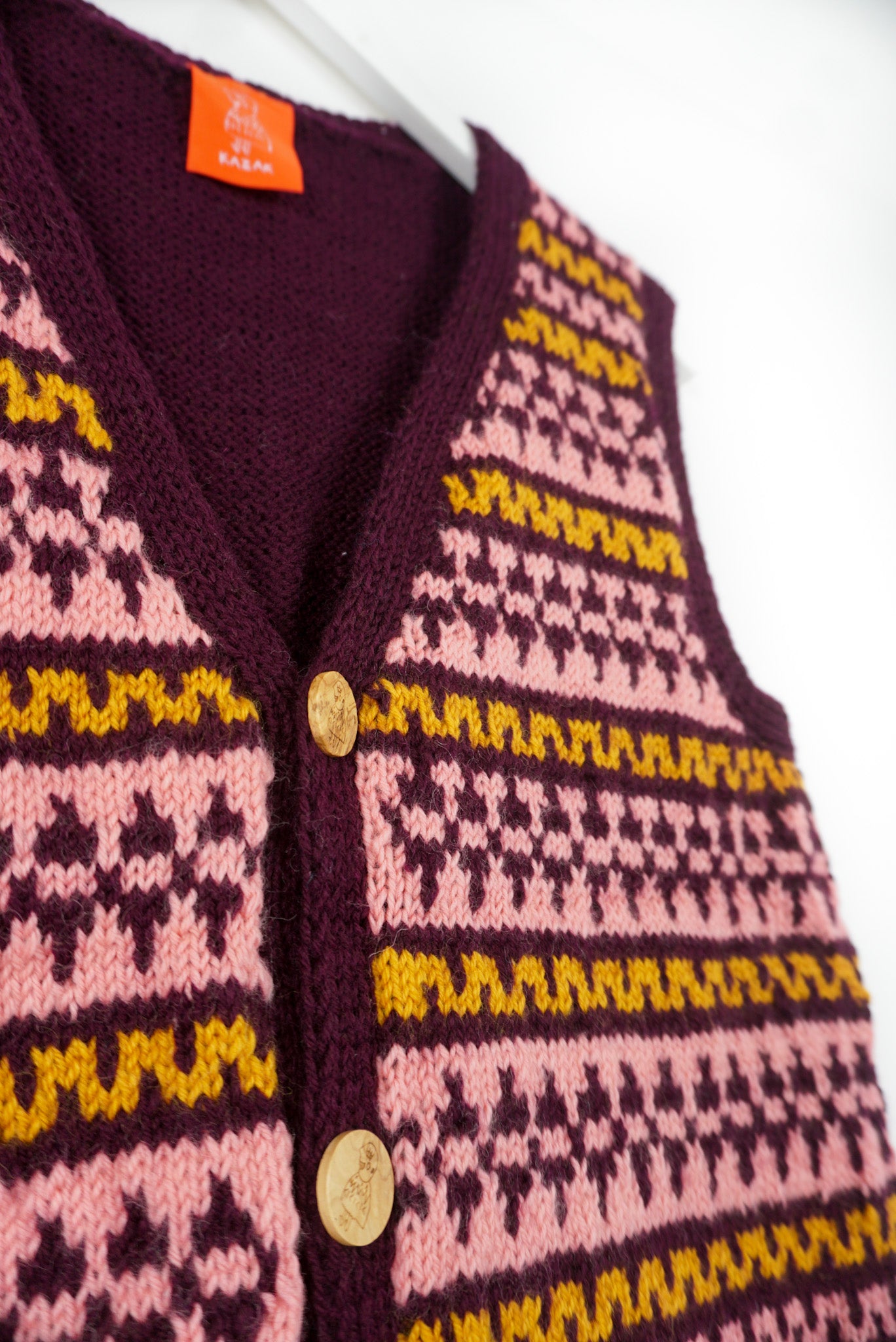 Close-up of a patterned cardigan with visible brand label on a white background