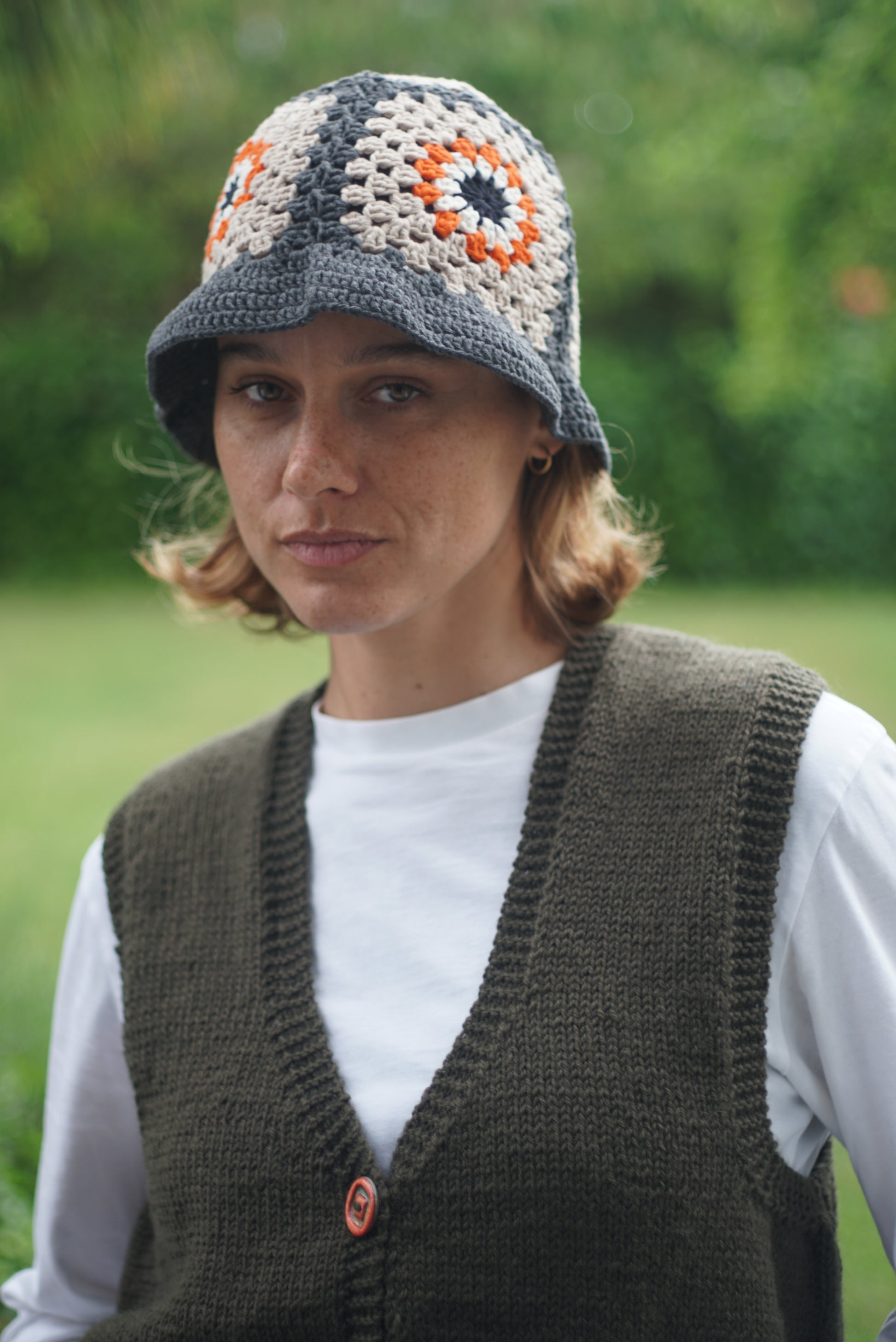 Hand Crochet cotton hat with orange floral patterns on it worn by a model, Glastonbury fashion, one off cotton hat