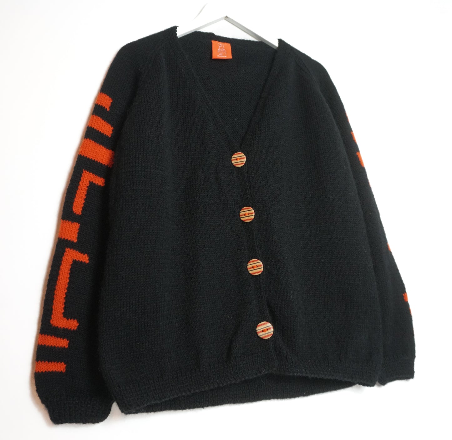 Black cardigan with orange buttons and sleeves on a white background