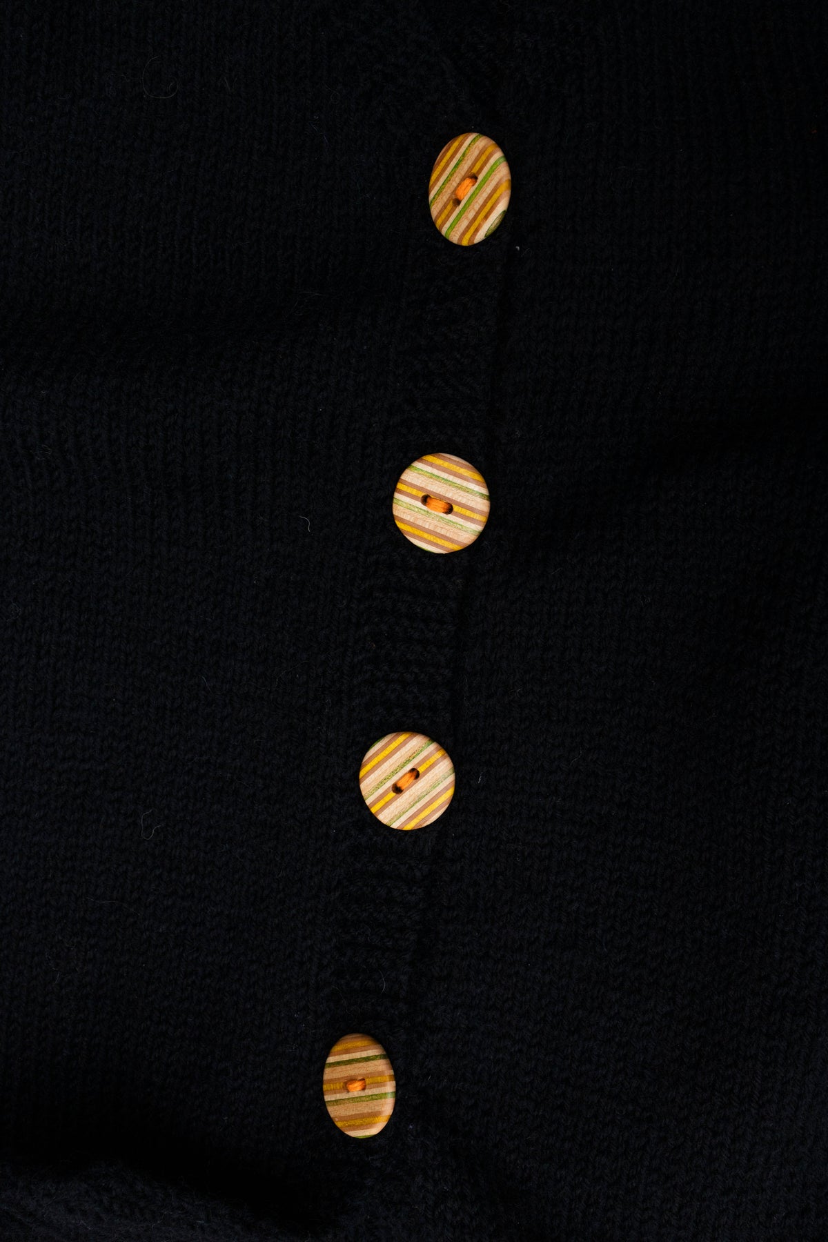 Black Buttoned Sleeveless Cardigan, close-up of buttons made from recycled skateboards, by Kazak Woolies