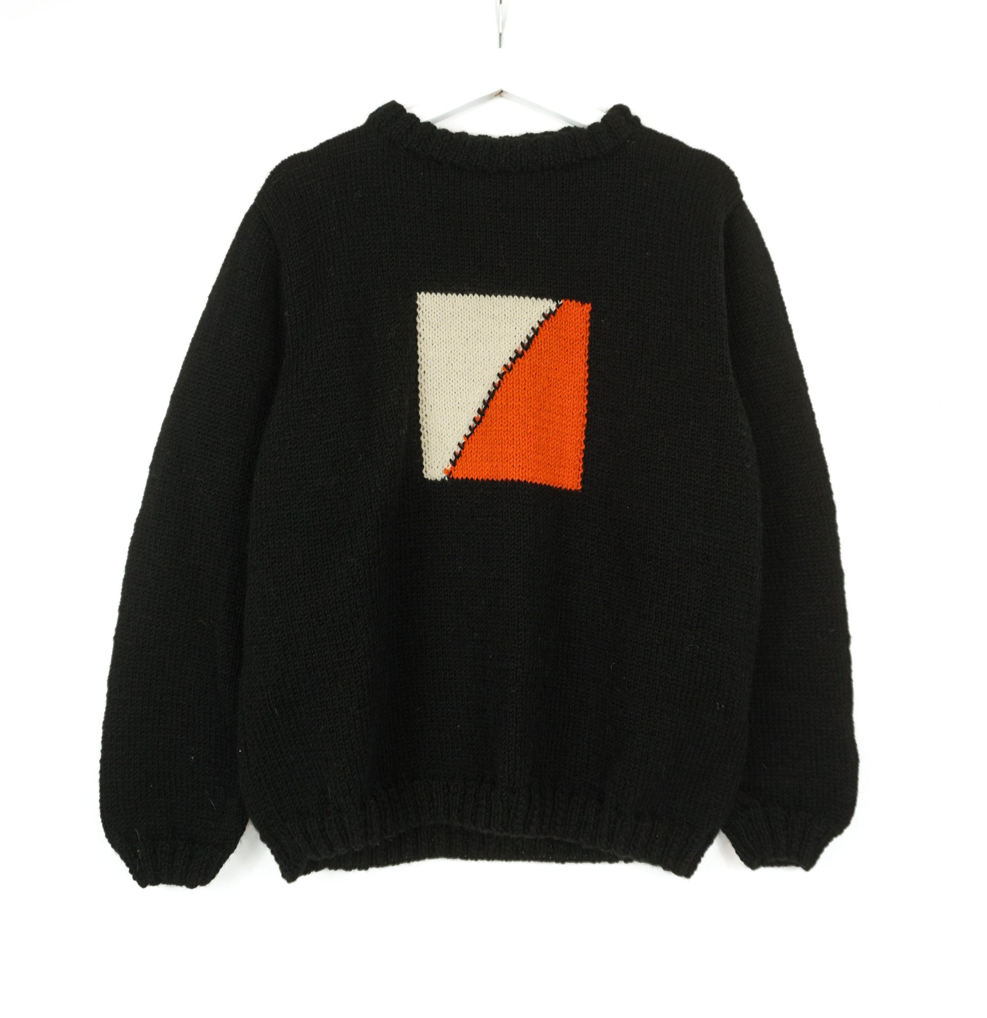 A black medium jumper with orange beige square pattern on it. 