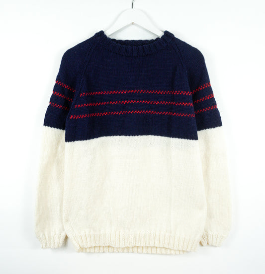 Navy and white sweater with red accents on a white background