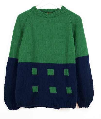Green and navy sweater with square pattern on a white background