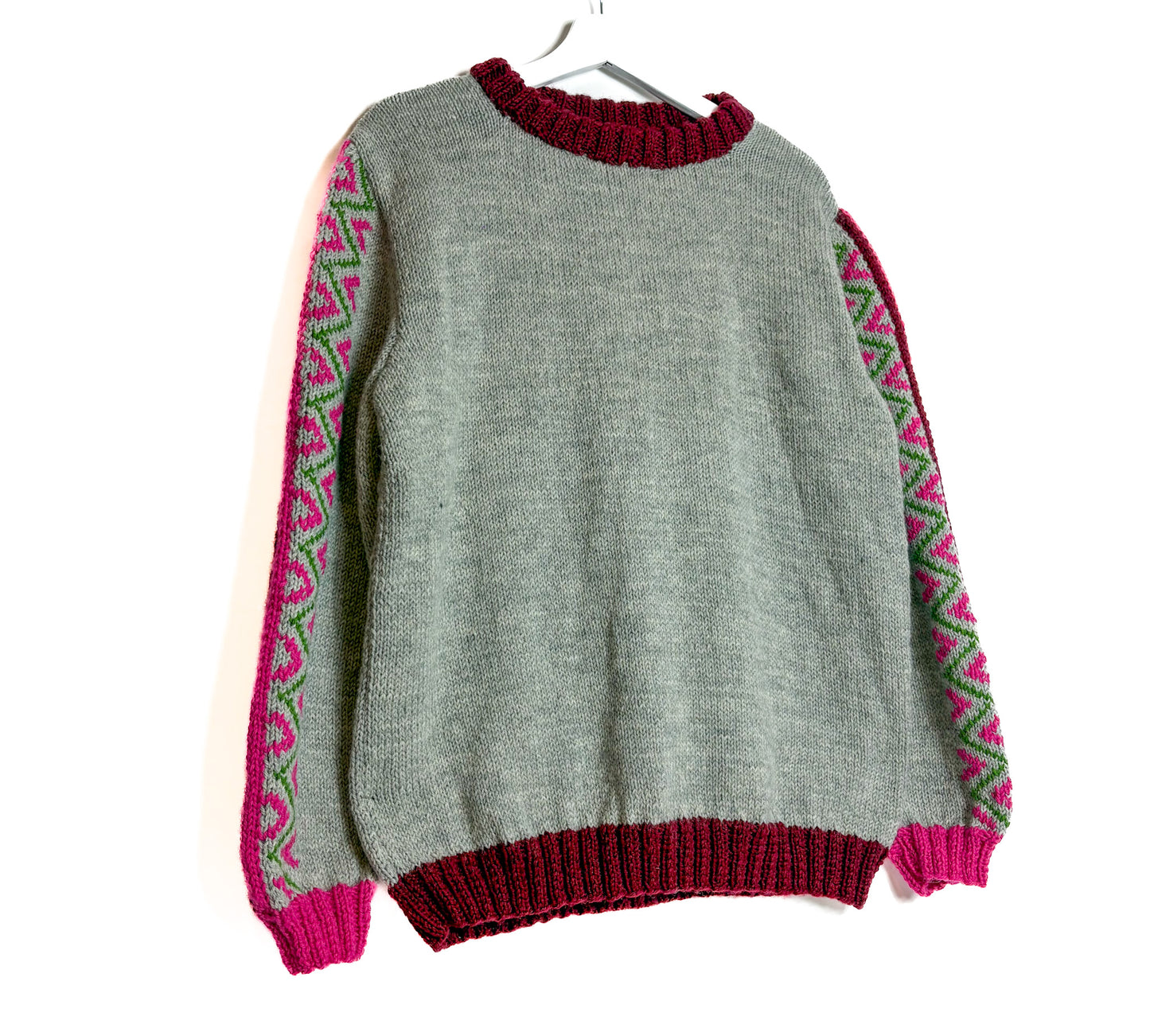 Gray sweater with red and pink patterned sleeves on a white background