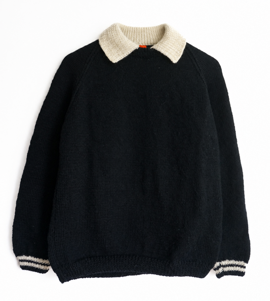 A black knit sweater with a contrasting cream-colored collar and striped cream-and-black ribbed cuffs and hem, displayed flat against a white background.