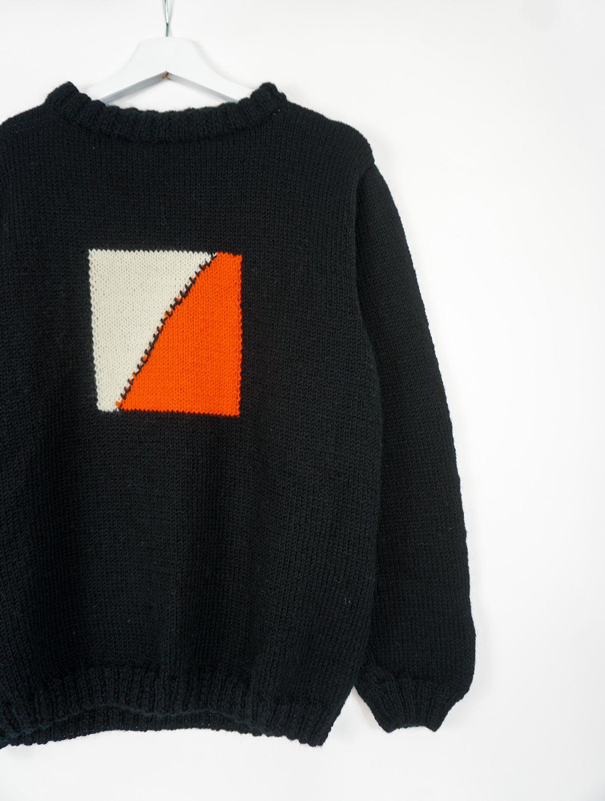 A black medium jumper with orange beige square pattern on it. 