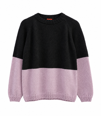A colorblock knit sweater with a black upper body and light pink lower body and sleeves, shown against a plain white background.