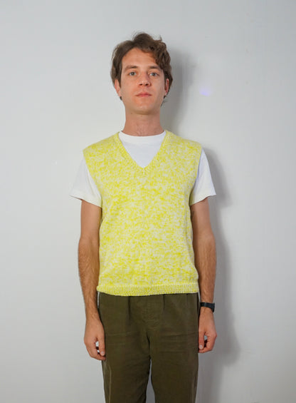 A sleeveless knit V-neck sweater vest in a bright yellow and white marled pattern, hanging on a white wooden hanger against a plain white background.